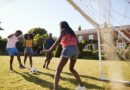 Two black adult couples playing football in garden