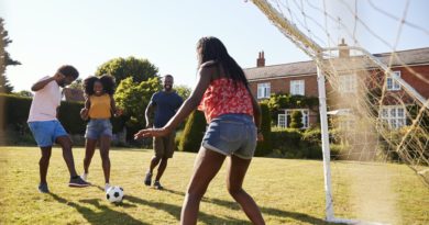 Two black adult couples playing football in garden