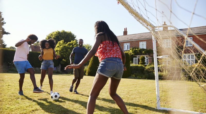 Two black adult couples playing football in garden