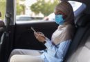 Black muslim businesswoman wearing face mask while using taxi during coronavirus pandemic