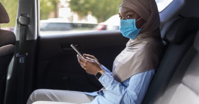 Black muslim businesswoman wearing face mask while using taxi during coronavirus pandemic